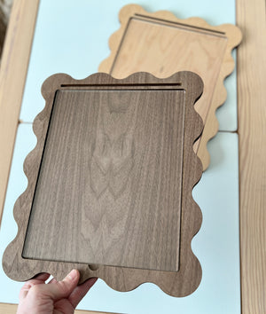 Hand holding a Walnut Laser Cut Writing Sensory Tray for 8.5 x 11 sheets with Dry Erase Inserts and Slot for Acrylic - Scalloped Design, made from rich walnut wood, handcrafted homeschool educational resources.
