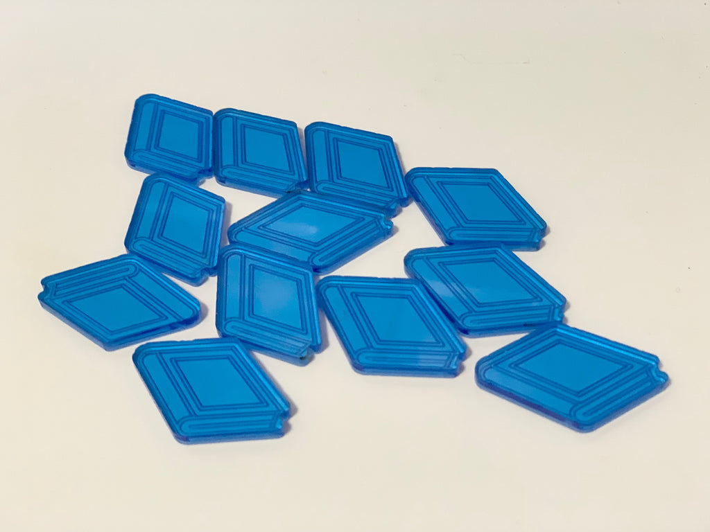 Translucent blue acrylic diamond-shaped game tokens scattered on a plain light background