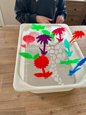 White tray with a stone path design holding colorful translucent acrylic pegs in various plant and garden shapes, showcasing STEM Insert – Acrylic Insert with Different Peg Options - Neighborhood, Veggie Garden, Flower Garden, Under the Sea + More, handcrafted, homeschool, education resources.