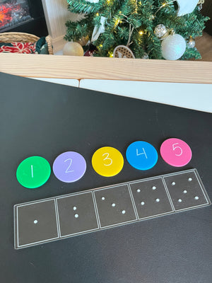 Black surface with five colorful discs numbered 1 to 5 above outlined dice dots in five boxes