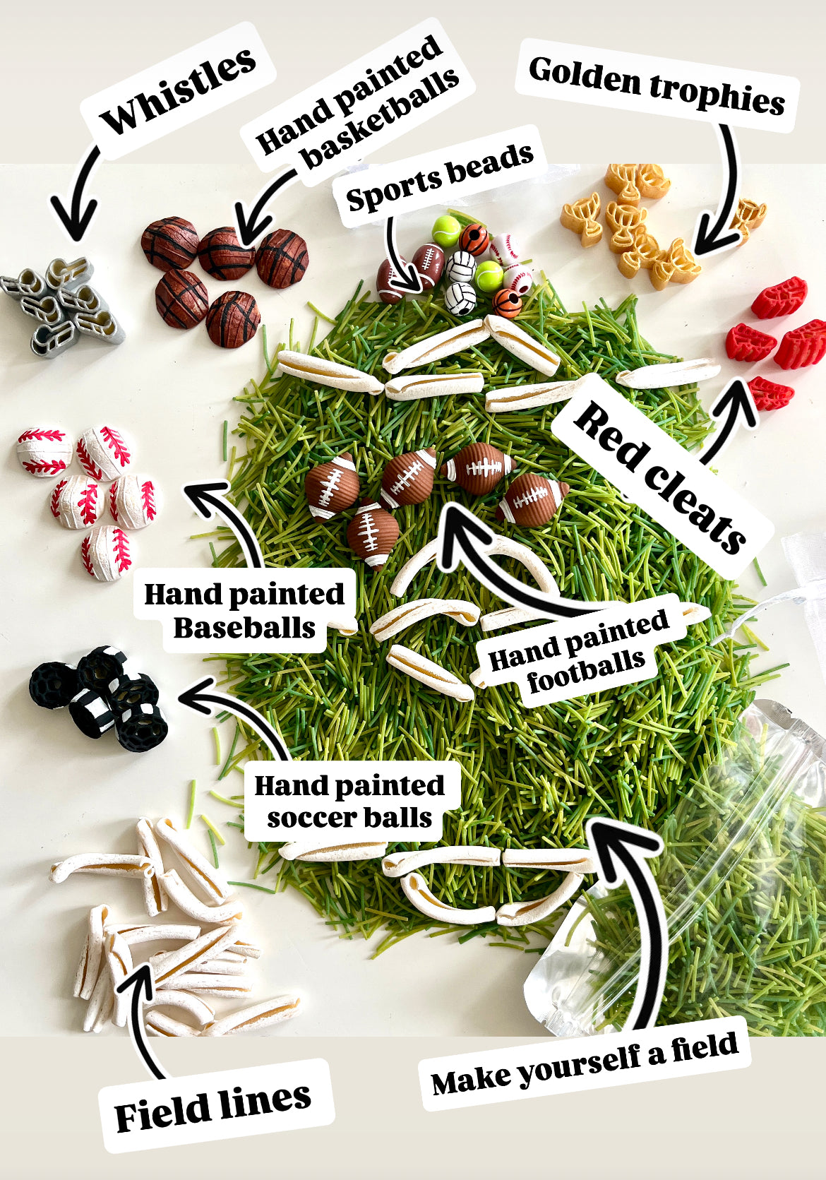 Assorted sports-themed miniature items including hand painted balls, whistles, red cleats, golden trophies, and field lines on faux grass