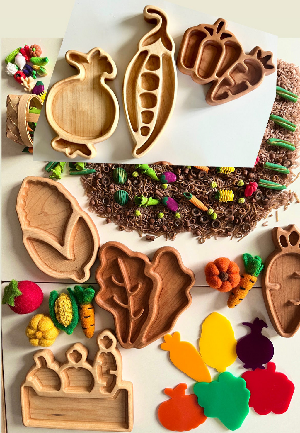 Variety of wooden vegetable-shaped trays with felt vegetables, colorful pasta, and craft materials on white surface
