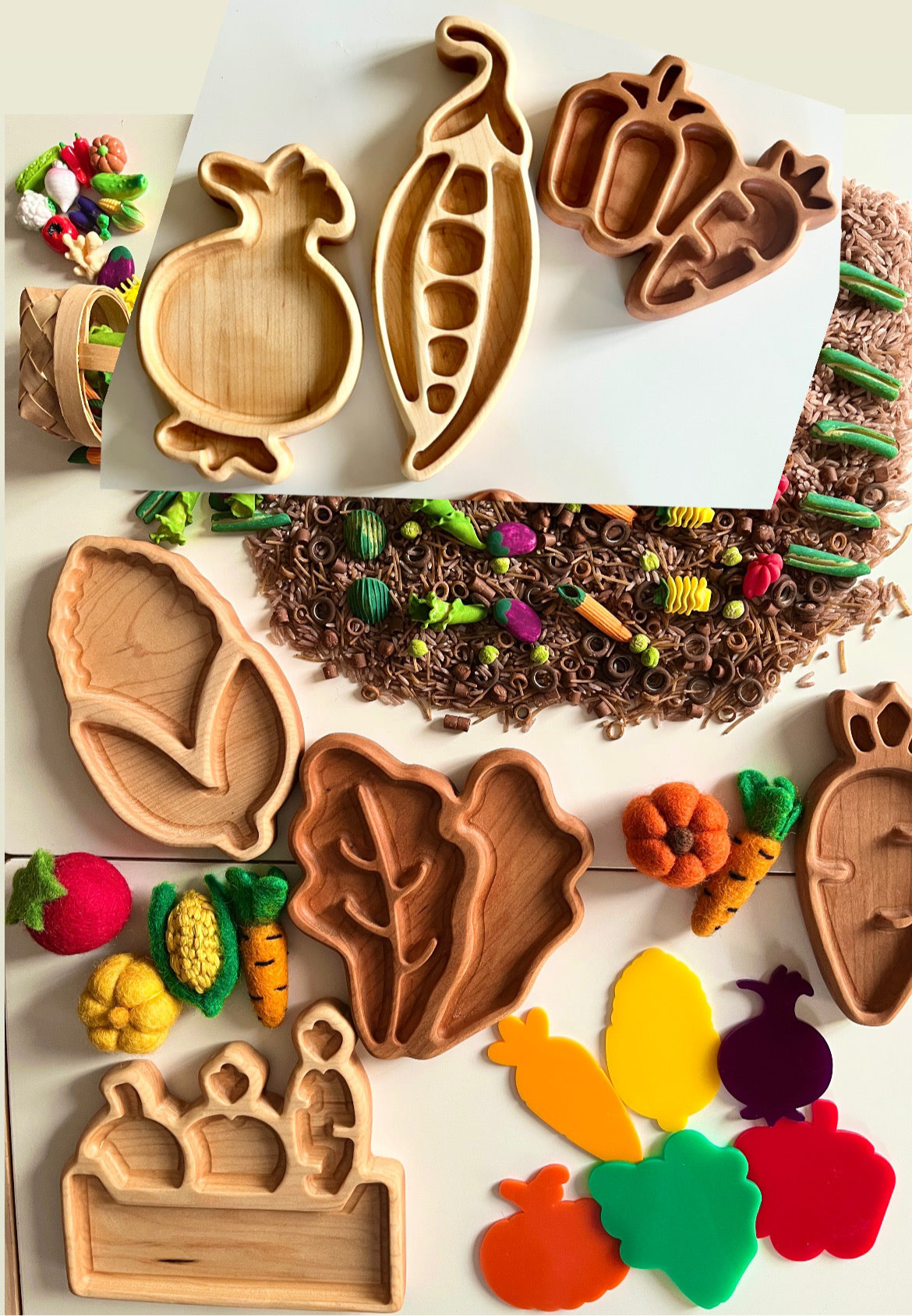 Variety of wooden vegetable-shaped trays with felt vegetables, colorful pasta, and craft materials on white surface