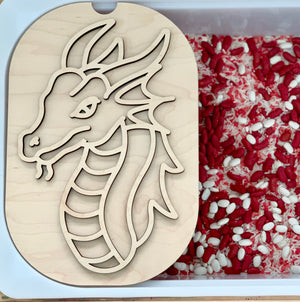 Wooden dragon stencil with carved outline resting on plastic container filled with red and white rice grains