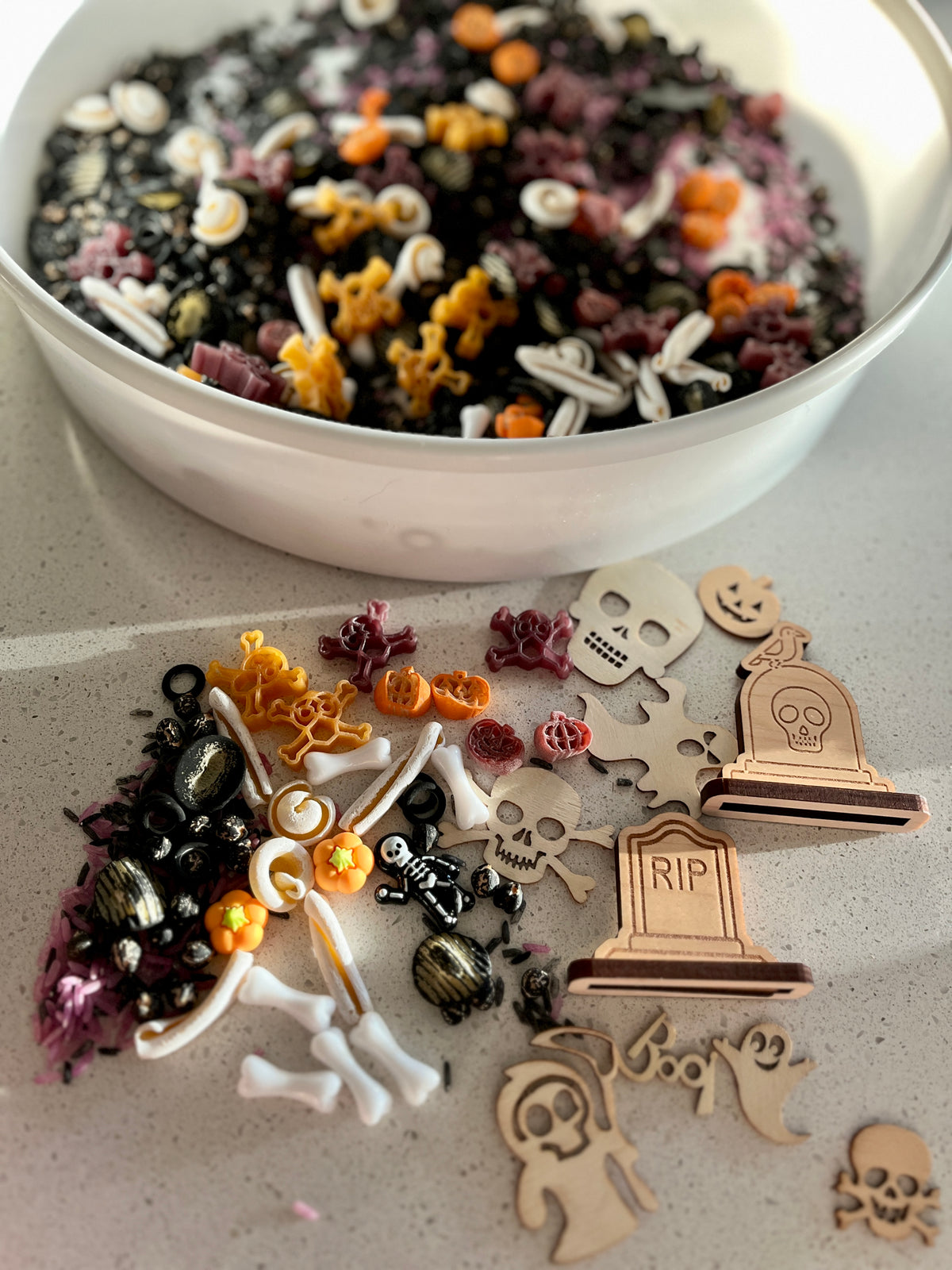 Assorted Halloween decorations including plastic skeleton parts, pumpkins, skulls, and wooden tombstone and ghost cutouts on a counter