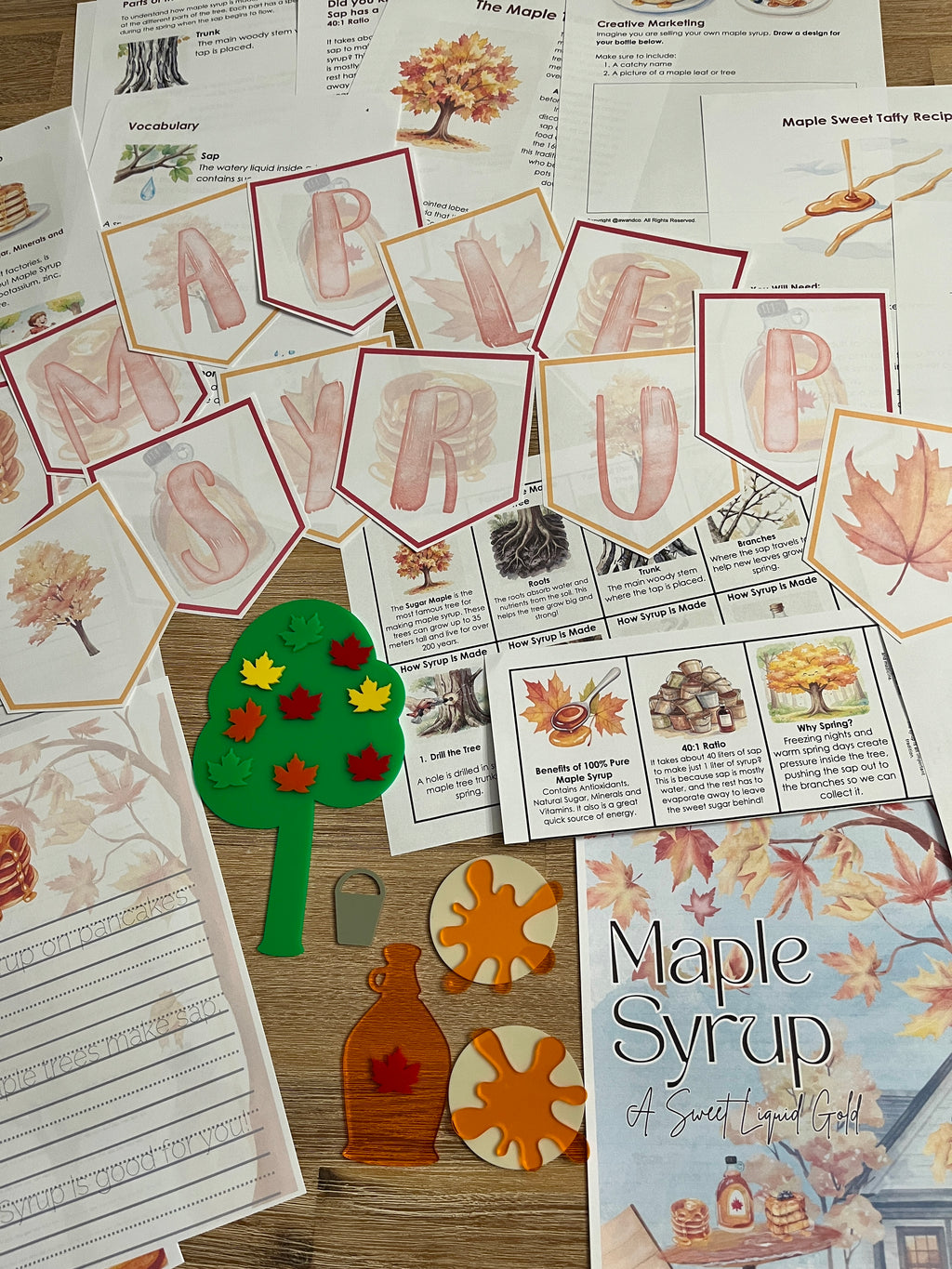 Digital Download | Maple Syrup Unit Study displaying themed printable banners, illustrated cards, worksheet pages, and maple syrup craft pieces with autumn leaf designs on a wood surface, handcrafted homeschool education resources.