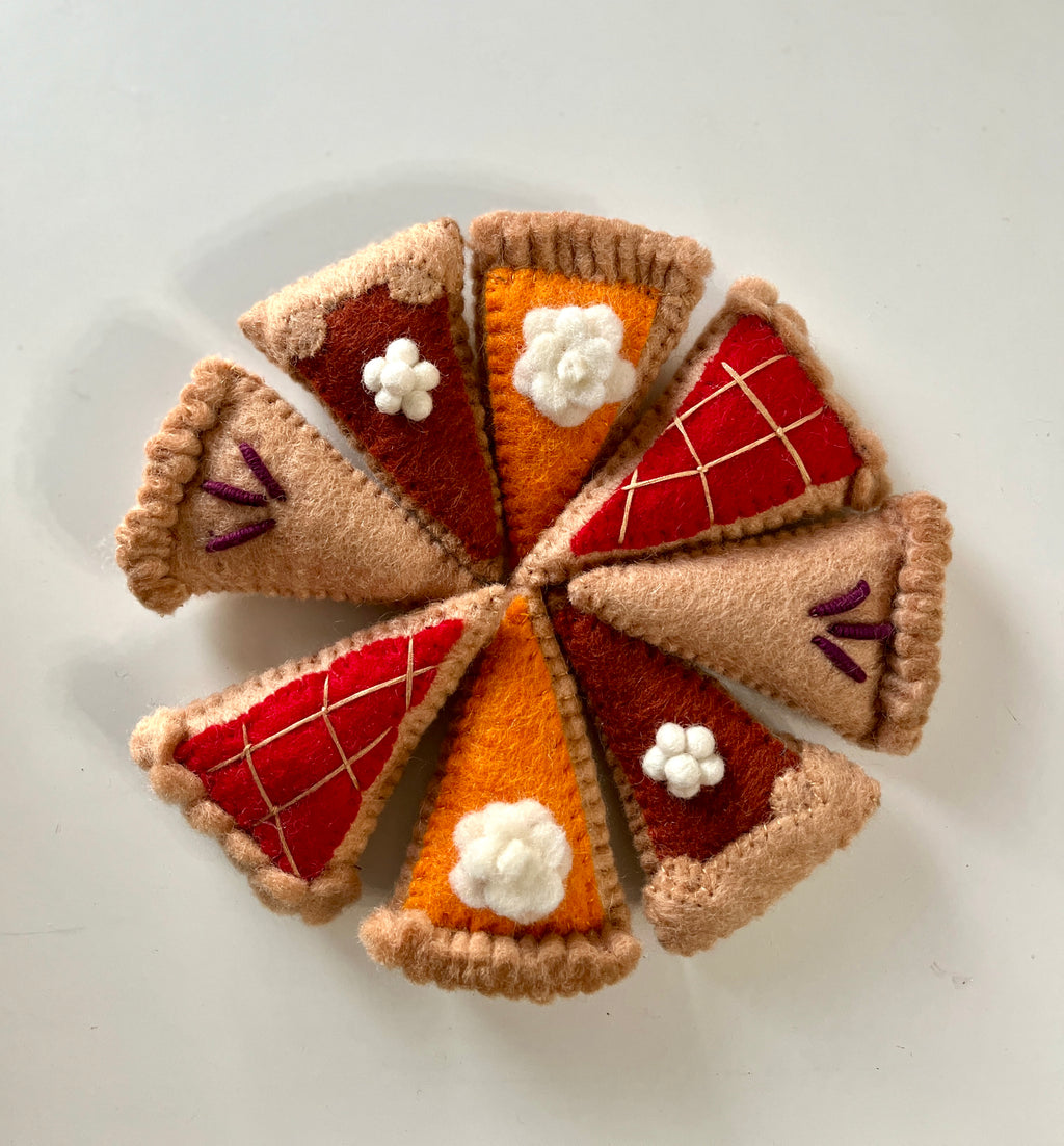 Eight felt pie slice ornaments in autumn colors arranged in a circle on a white background