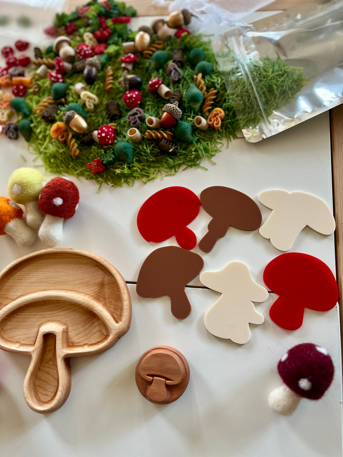 Wooden and felt mushroom shapes, colorful small craft pieces, and a wooden mushroom tray on white surface
