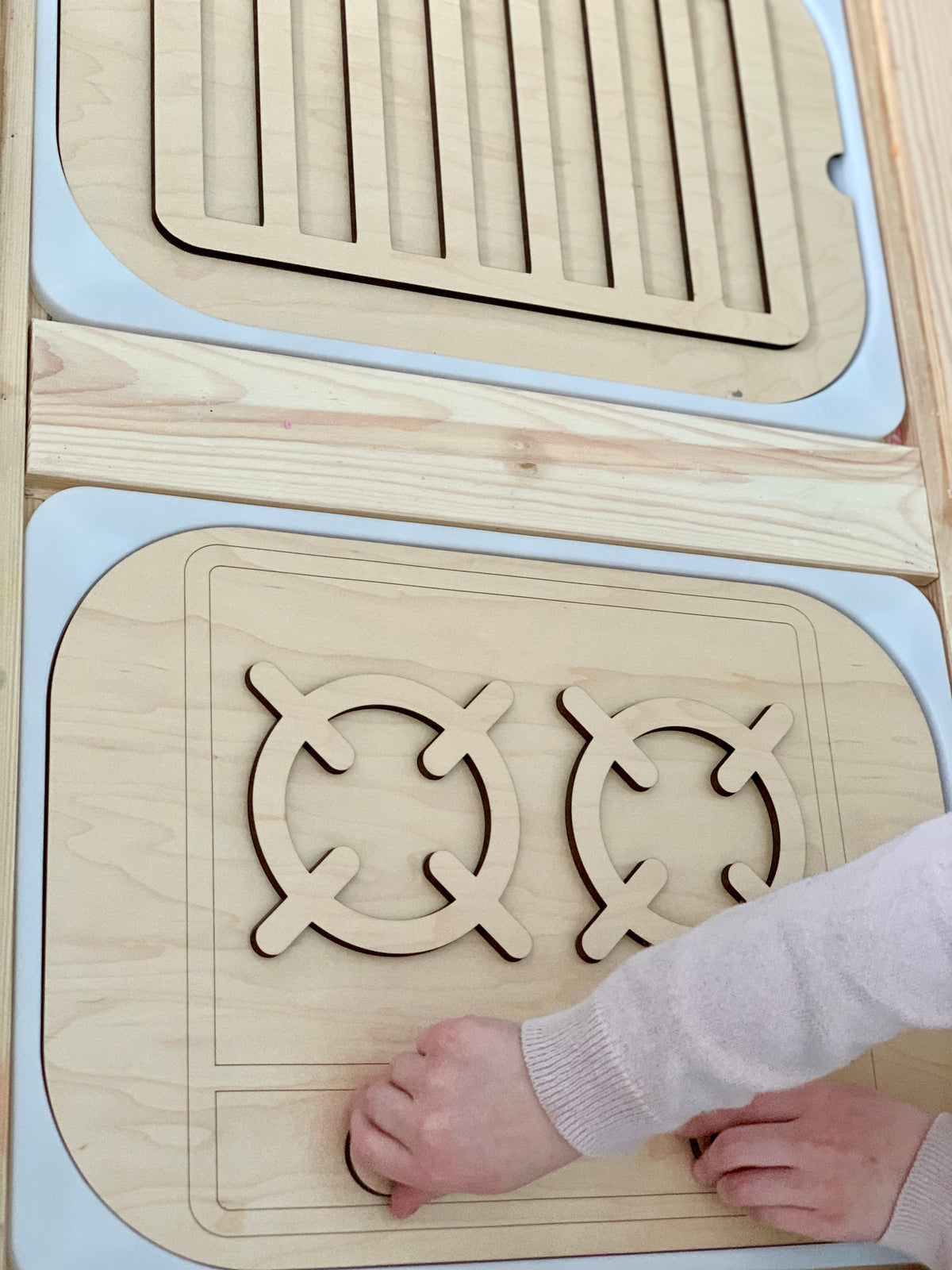 Wooden stove top and oven inserts with turnable knobs on maple plywood and acrylic base on light wood surface