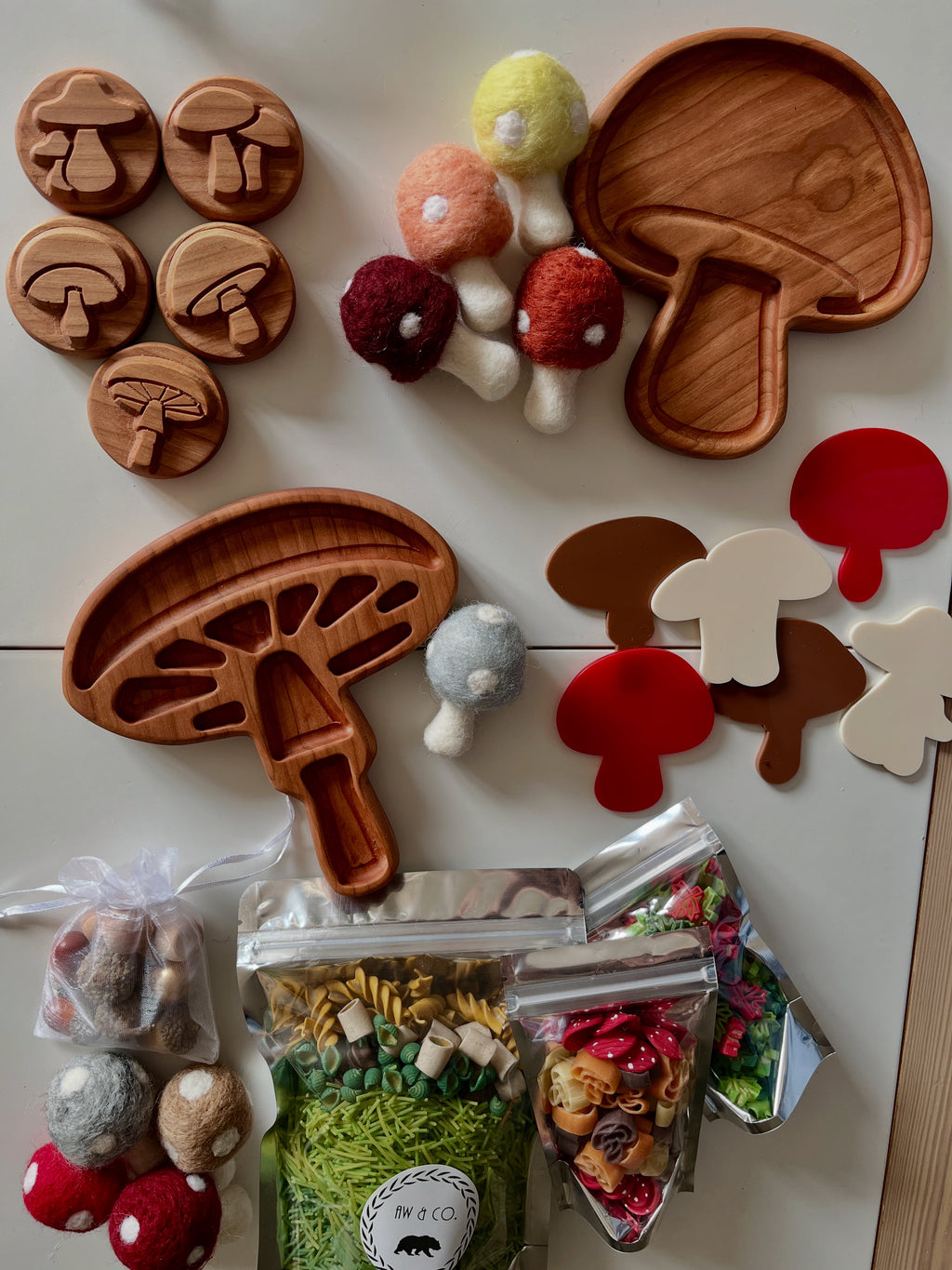 Wooden mushroom trays, felt mushroom toys, plastic mushroom shapes, and craft supplies on a white surface