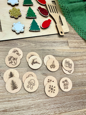 Wooden Christmas memory game discs with engraved holiday icons on light wood table surface with game parts nearby
