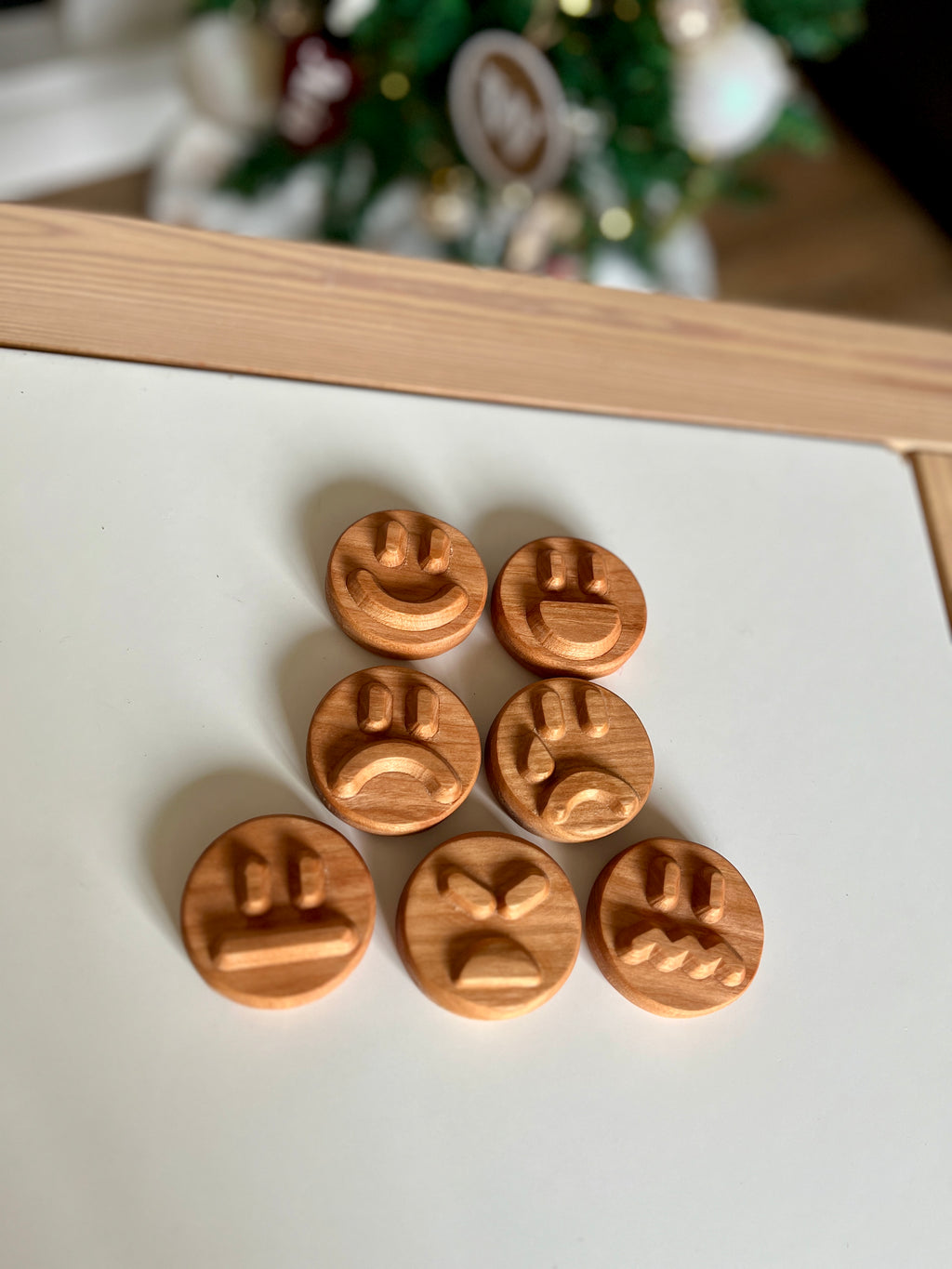 Set of seven round wooden tokens engraved with various expressive face designs on white surface with blurred background