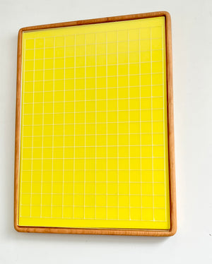 Tall wooden rectangular writing sensory tray holding yellow dry erase insert with white grid lines on white background