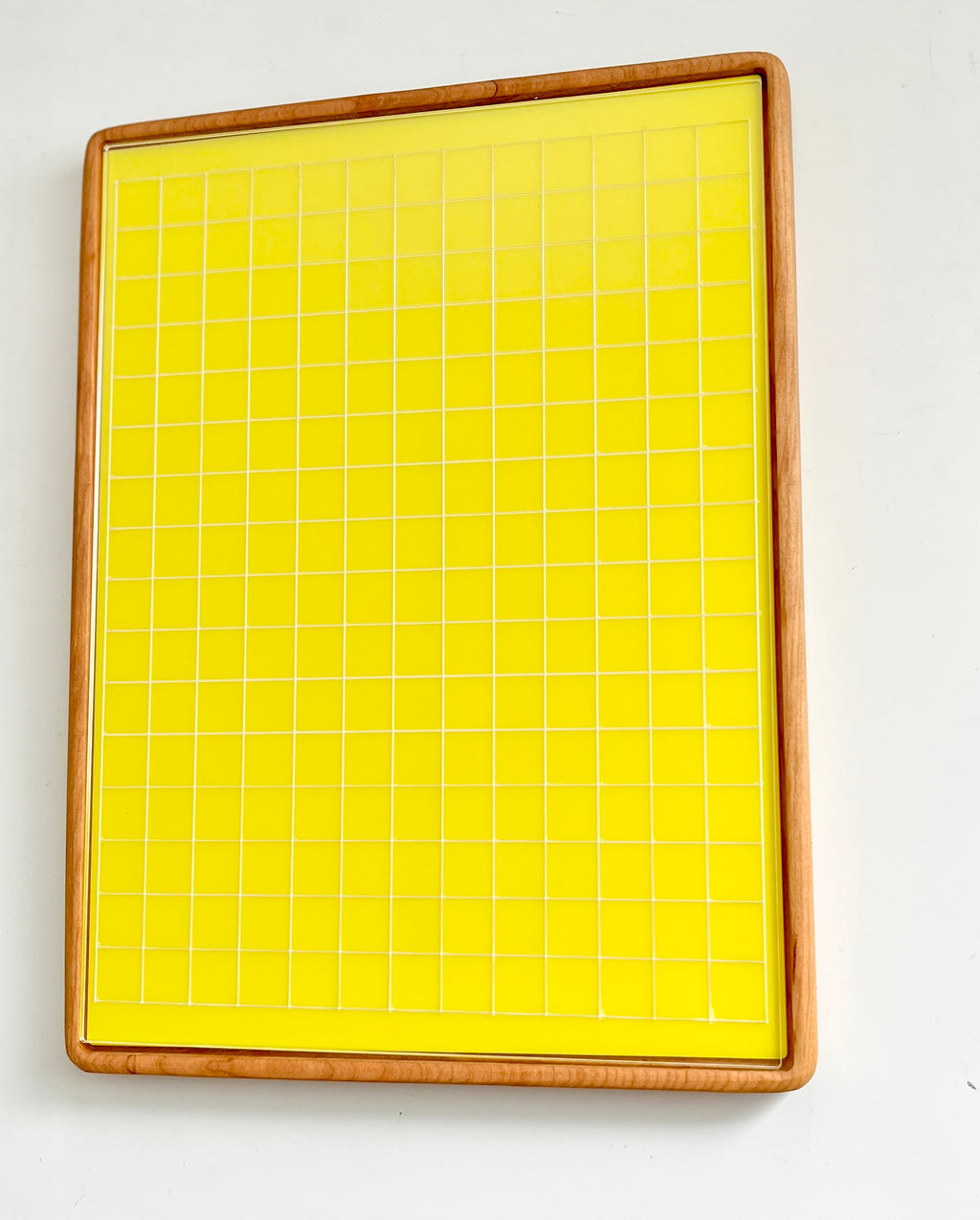 Tall wooden rectangular writing sensory tray holding yellow dry erase insert with white grid lines on white background