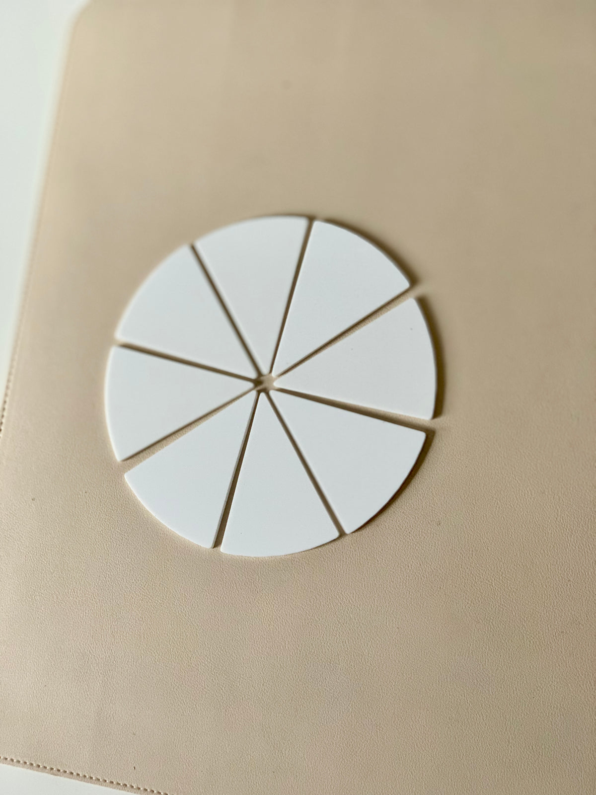 Set of eight white dry erasable pizza or pie slice shapes arranged in a circle on beige surface