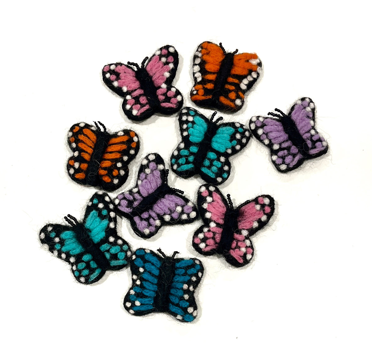 Collection of small felt butterfly shapes in pink, orange, blue, and purple with black and white spotted details on white background