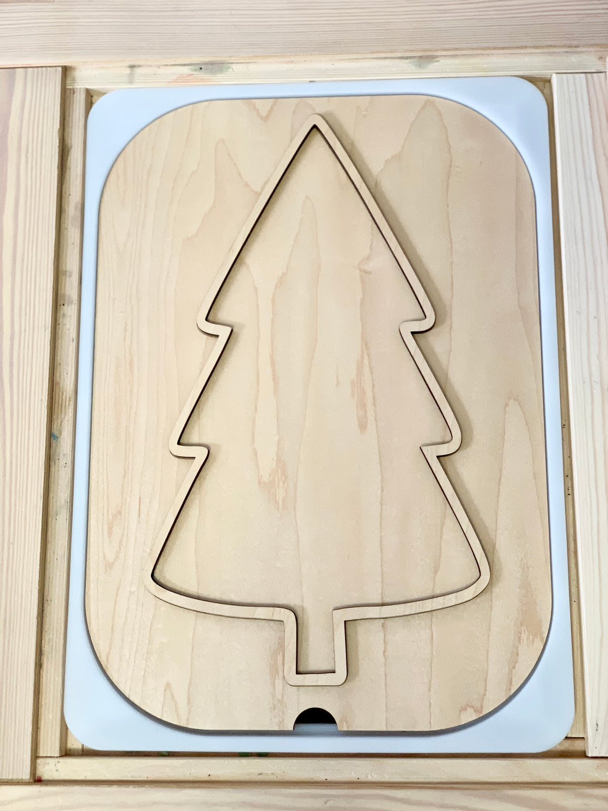 Unfinished light wood puzzle board with a large Christmas tree shape cutout and smooth rounded edges