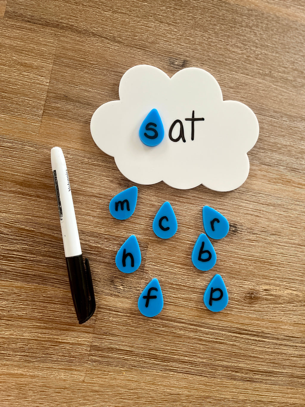 Little Dry Erasables - Cloud with Raindrops featuring a handcrafted white cloud board with blue wooden raindrop letter pieces and a black dry erase marker on a wooden surface, homeschool education resources.