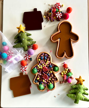 Gingerbread man and house-shaped trays with colorful beads, pom-poms, felt Christmas trees, and candy decorations scattered around