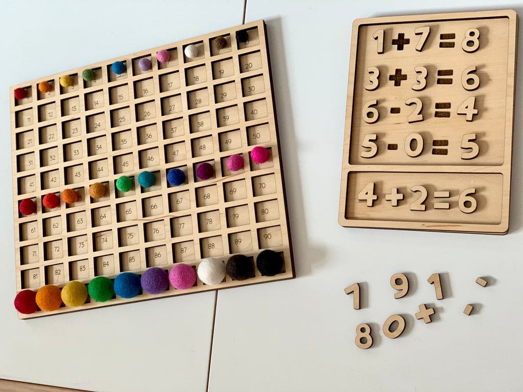 Laser cut wooden 100 frame hundred sorting board with colorful felt balls and wooden math puzzle pieces on white table