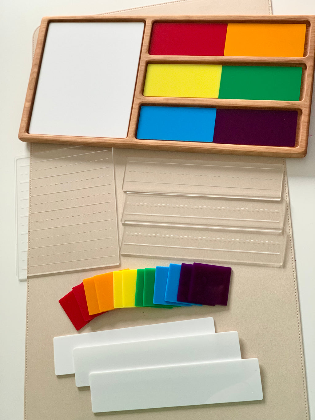 Wooden tray with stacked colorful transparent squares and white rectangular panels on a beige surface
