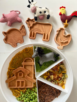 Wooden farm animal trays shaped like pig, cow, and chicken with felt farm animals and a divided tray of colorful pasta and noodles