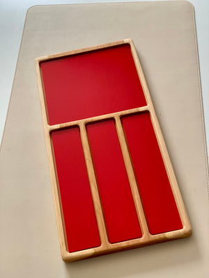 Wooden organizer tray with one large and three narrow deep compartments featuring red interiors on a beige surface