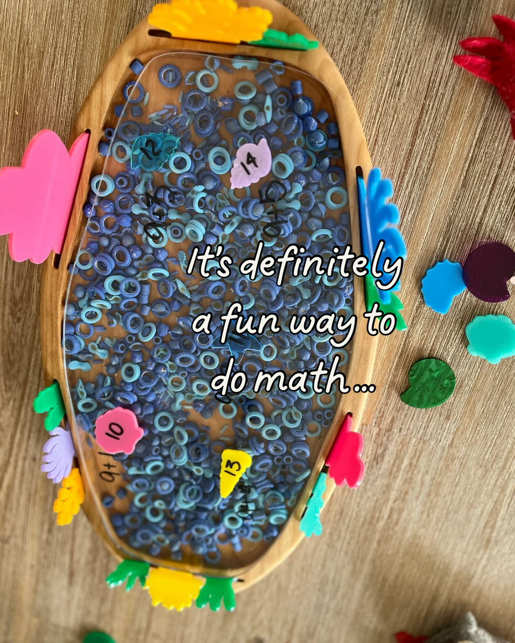 Multipurpose Oval Sensory Tray featuring a wooden frame filled with blue sensory rings, colorful number tags, and assorted colorful wooden shapes, handcrafted, homeschool, education resources.