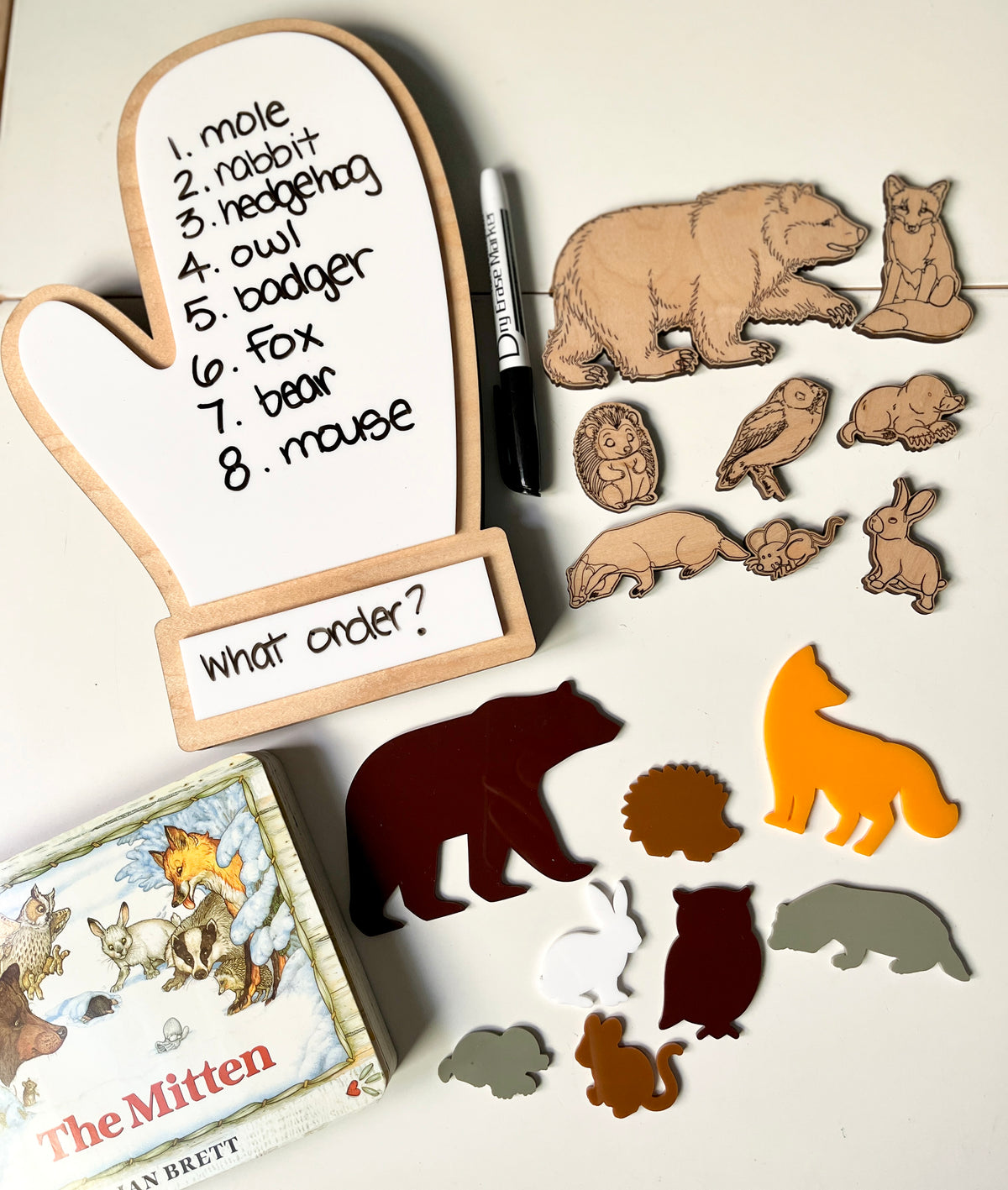 The Mitten Wooden Animals and/or Little Dry Erasables with Mitten Interactive Learning Set featuring natural wood and colorful animal figures, a mitten-shaped dry-erase board with handwritten animal names and questions, unique handcrafted homeschool education resources.