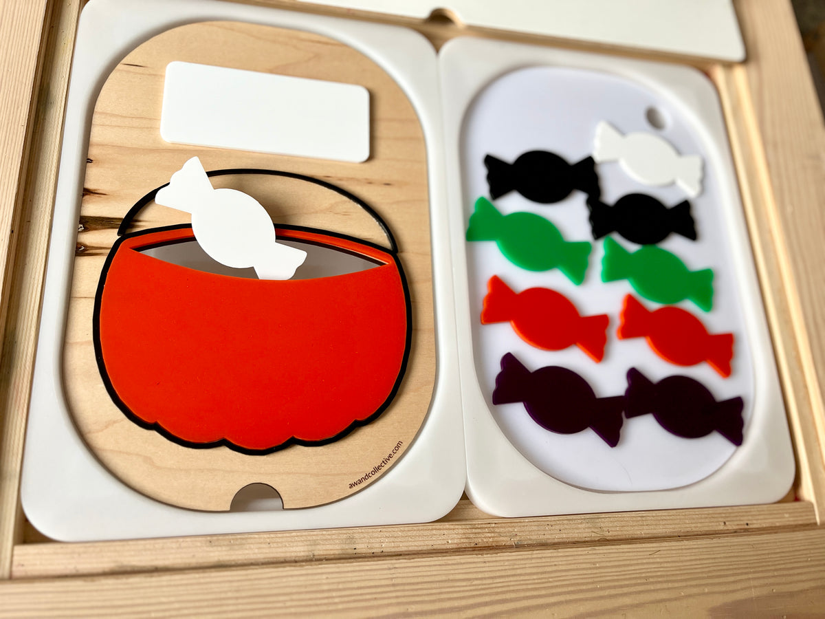 Wooden puzzle pieces featuring a red basket and various colored candy shapes arranged on white trays
