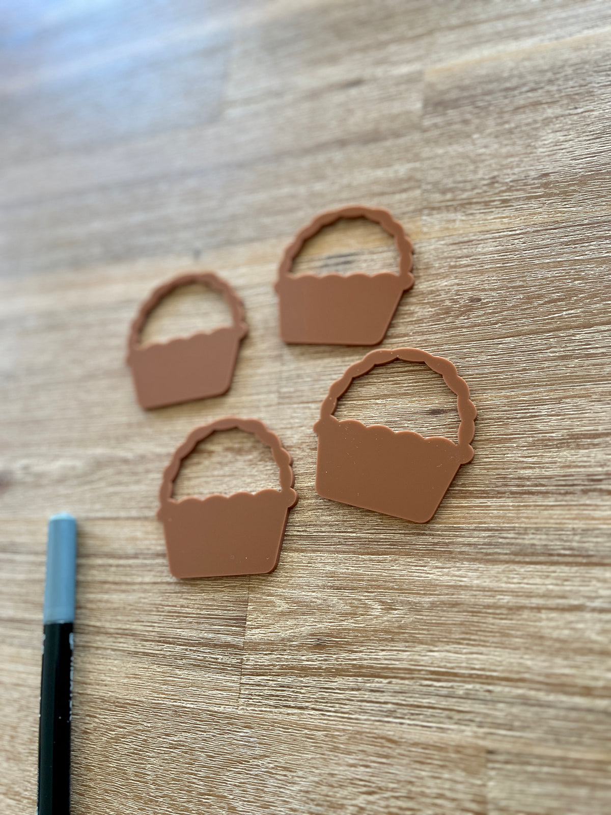 Four small terracotta-colored basket shapes arranged on a wood surface next to a black marker, Little Dry Erasables - Set of 5 Baskets, handcrafted, homeschool, education resources.