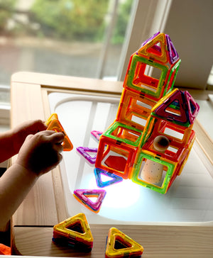 Frosted acrylic Flisat table top with colorful magnetic building tiles and wooden ball on lighted surface in wooden frame