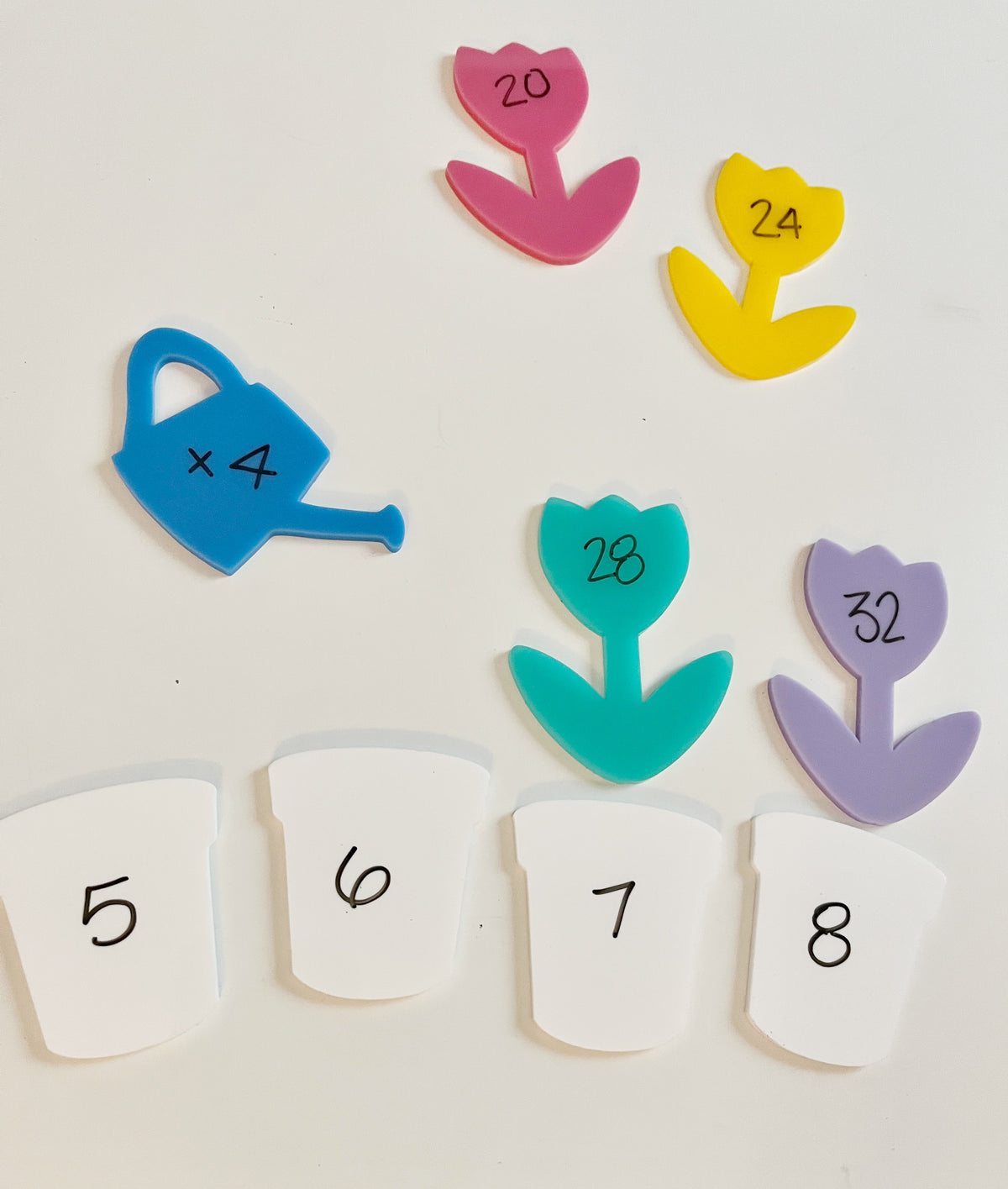Little Dry Erasables - Pastel Flowers with White Pots and Watering Can showing colorful flower shapes with multiplication facts, white pots numbered 5 to 8, and a blue watering can, handcrafted homeschool education resources.