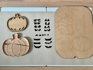 Laser cut pumpkin-shaped wooden sensory trays with carved pumpkin faces and removable facial feature pieces on table mat