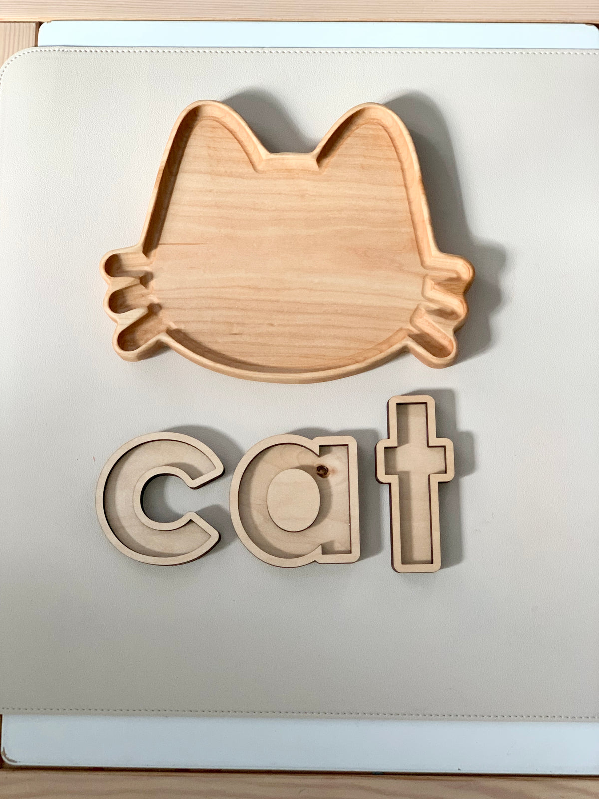 Wooden cat-shaped sensory tray with matching wooden letters c, a, t on white background