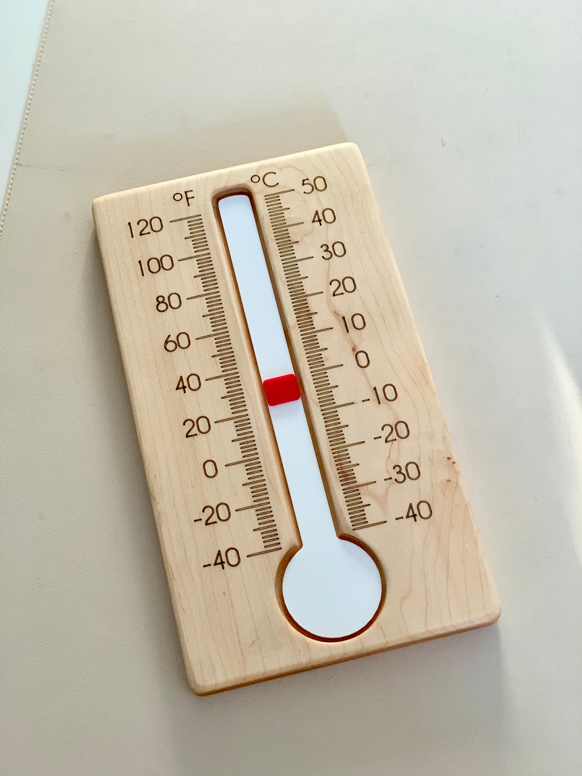 Wooden thermometer with Fahrenheit and Celsius scales showing a temperature around 70°F and 20°C on white surface