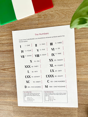 Digital Download | Roman Numerals, Their History & DeCoding Activity showing a printed chart of Roman numerals with symbols and values on a wooden surface next to an Italian flag themed object and a green leaf, handcrafted homeschool education resources.