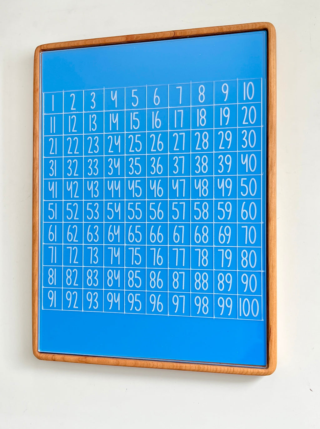 Tall wooden rectangular writing sensory tray holding blue dry erase insert with white numbers grid from 1 to 100