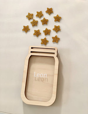 Wooden jar-shaped frame with the name Leon and scattered glittery gold star tokens on a light background