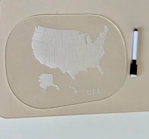 Clear acrylic board with etched USA map and state outlines beside a black and white dry erase marker on beige surface