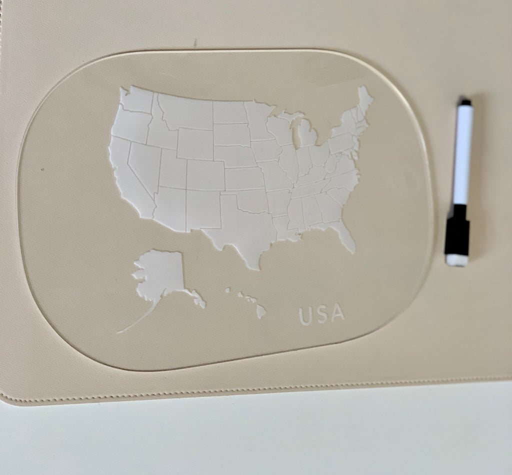 Clear acrylic board with etched USA map and state outlines beside a black and white dry erase marker on beige surface
