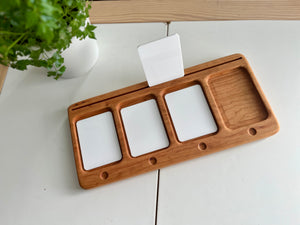 Rectangular wooden organizer tray with three white card slots and an empty compartment on a white tiled surface
