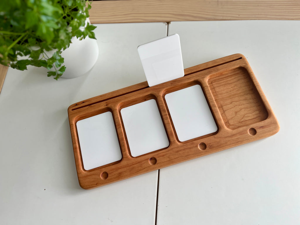 Rectangular wooden organizer tray with three white card slots and an empty compartment on a white tiled surface