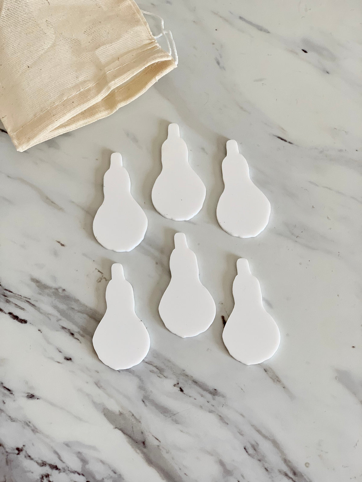 Set of six white gourd-shaped dry erase boards with a beige drawstring storage bag on marble surface