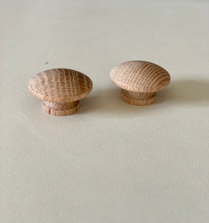 Two rounded natural wood knobs with visible grain details resting on a light surface