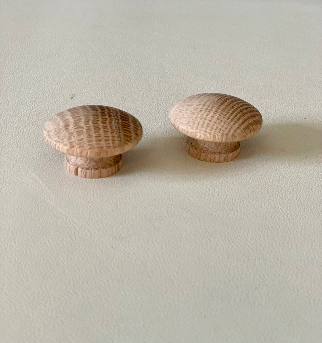 Two rounded natural wood knobs with visible grain details resting on a light surface