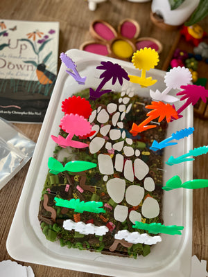 White tray with a nature-inspired base featuring colorful translucent acrylic pegs shaped like flowers and plants arranged along a stone path, showcasing STEM Insert – Acrylic Insert with Different Peg Options - Neighborhood, Veggie Garden, Flower Garden, Under the Sea + More, handcrafted, homeschool, education resources.
