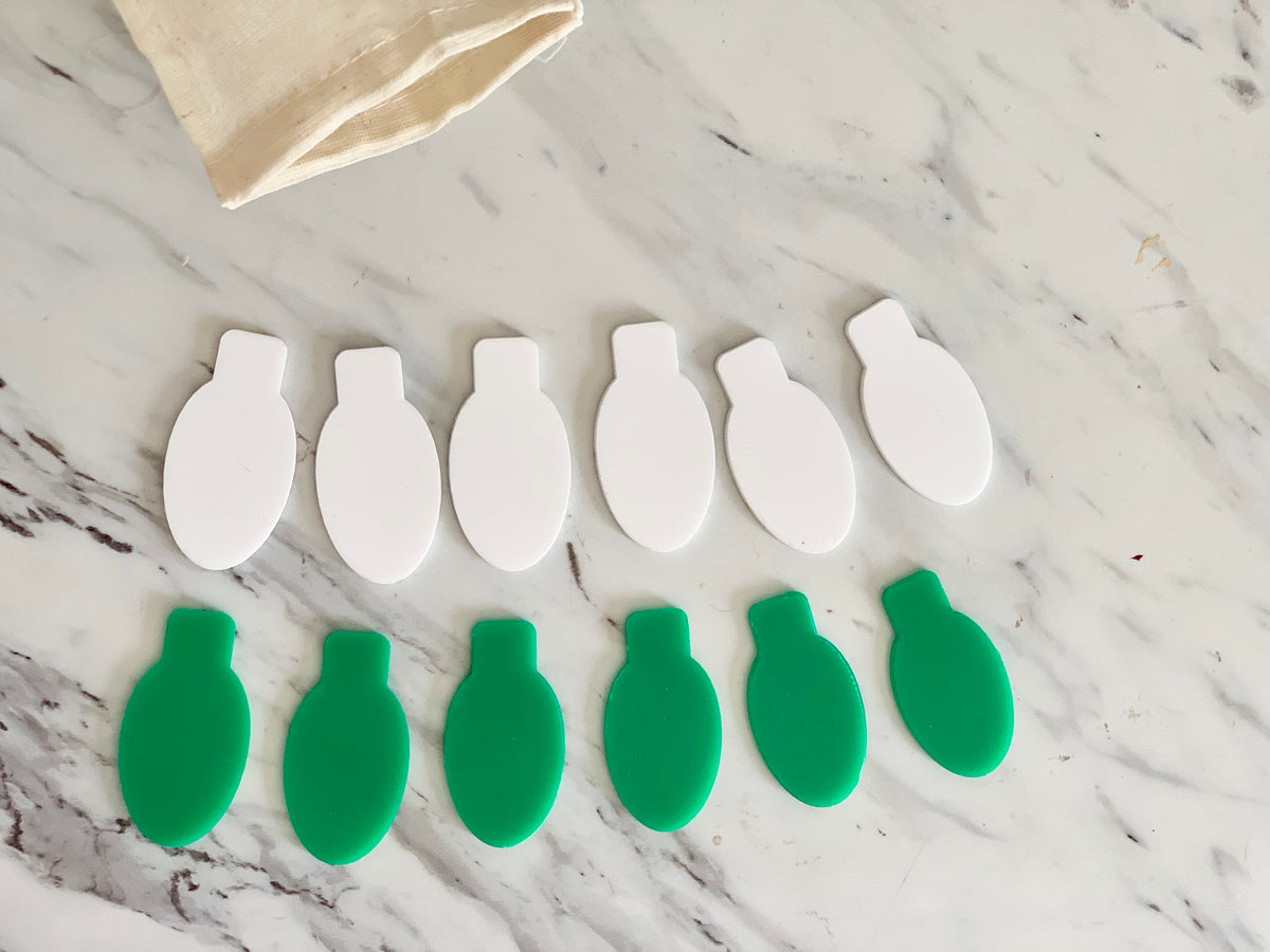 Set of six lightbulb-shaped dry erasable boards in white and green colors on marble surface with cloth bag corner