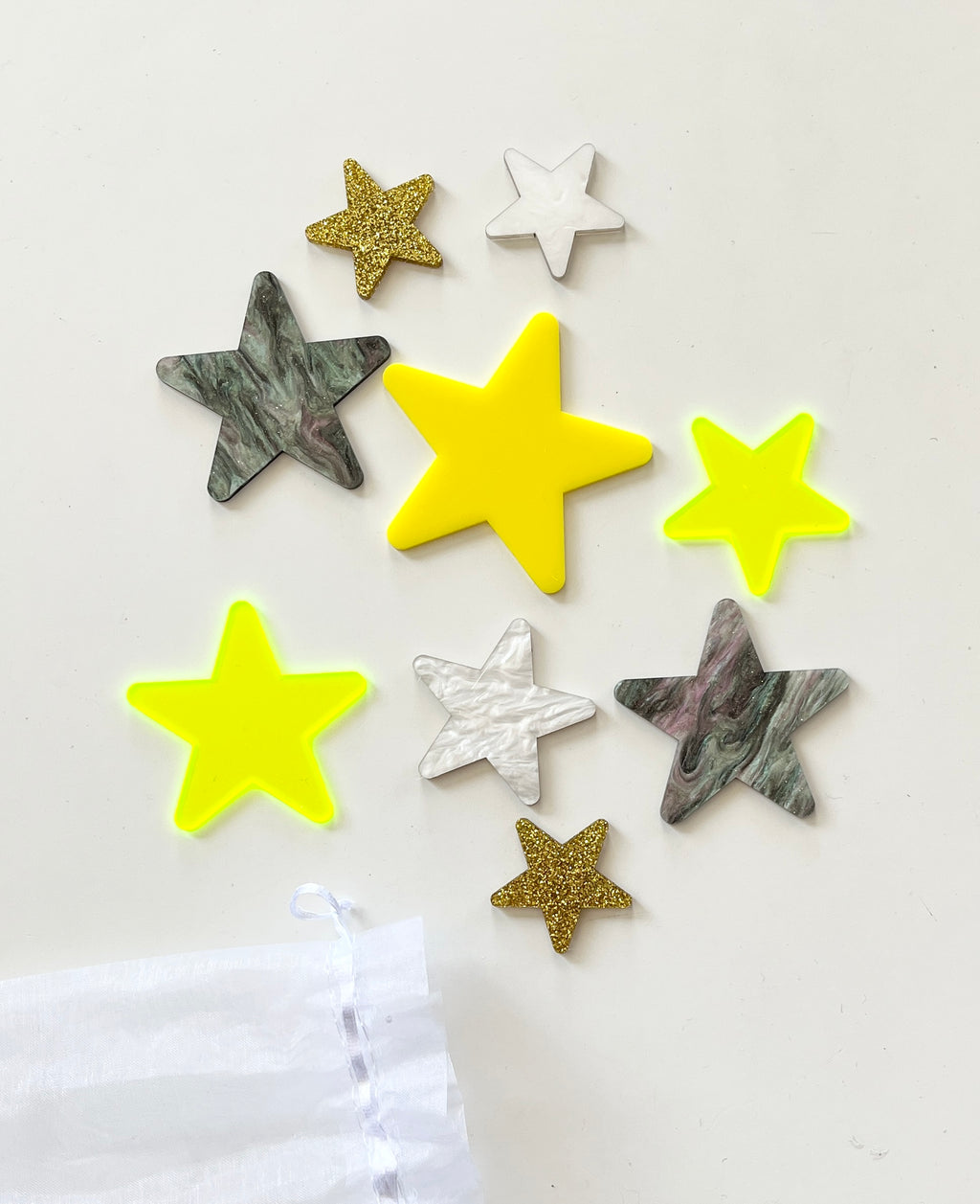 Assorted star shapes in neon yellow, gold glitter, white marble, and green marble textures on a white background