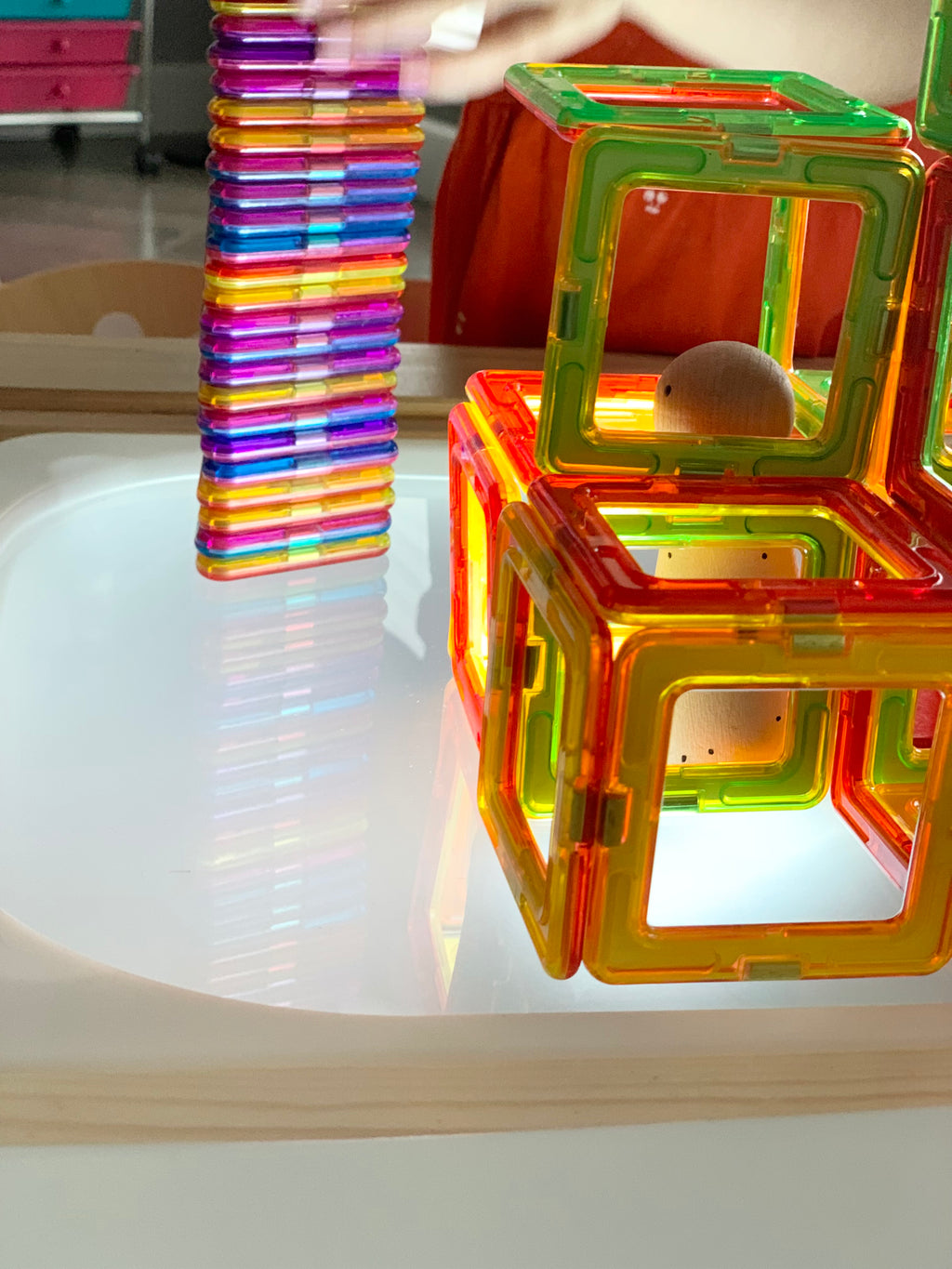 Light table with frosted acrylic top illuminating colorful magnetic building cubes and tiles on wooden frame